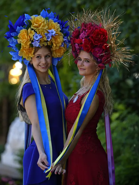 Maria (kiri) mengenakan topi bermotif bendera Ukraina berpose dengan Anastasia saat foto pada hari pertama pertemuan balap kuda Royal Ascot, di Ascot Racecourse, di Ascot, Inggris, Selasa (14/6/2022). (AP Photo/Alastair Grant)