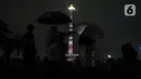 Pengunjung menyaksikan penampilan video mapping saat malam pergantian tahun di kawasan Monumen Nasional, Jakarta, Selasa (31/12/2019). Meski Jakarta diguyur hujan sejak Selasa (31/12) sore, warga tetap mendatangi kawasan Monas untuk merayakan malam pergantian tahun. (Liputan6.com/Helmi Fithriansyah)