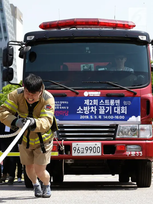 Ekspresi petugas pemadam kebakaran Lim Sung-joo saat menarik sebuah truk pemadam kebakaran dengan seutas tali dalam acara Safe Seoul Festival di Seoul, Korea Selatan, Kamis (9/5/2019). Safe Seoul Festival ditujukan bagi anak-anak dan keluarga. (AP Photo/Ahn Young-joon)