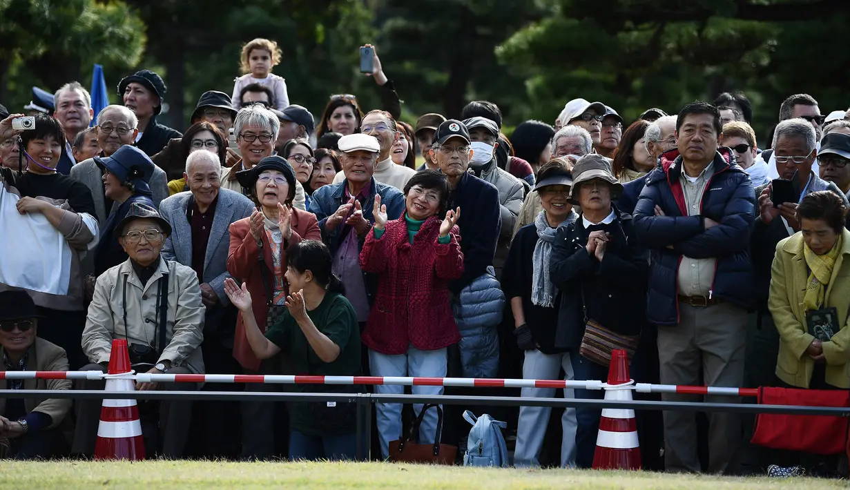 Sejumlah warga menyaksikan perayaan nasional untuk menandai penobatan Kaisar Jepang Naruhito di depan Istana Kekaisaran di Tokyo (9/11/2019). Kaisar Naruhito menggantikan posisi ayahnya, Akihito yang menjadi kaisar pertama yang turun tahta. (AFP Photo/Charly Triballeau)
