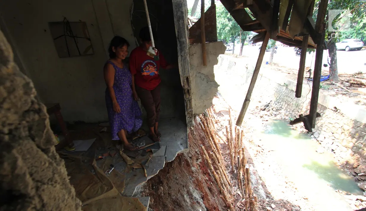 Warga mengamati bagian belakang rumahnya rusak akibat terkena longsor di pinggir kali Bintaro Utara, Pesanggrahan, Jakarta, Kamis (20/9). Hujan lebat mengakibatkan sebanyak lima rumah di pinggir kali tersebut longsor. (Liputan6.com/Angga Yuniar)