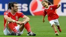 Gareth Bale duduk menyaksikan keceriaan putrinya, Alba Violet usai laga melawan Irlandia Utara pada Piala Eropa 2016 di Parc des Princes, Paris, (25/6/2016). Wales Menang 1-0. (EPA/Georgi Licovski)