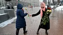 Seorang aktivis dari Asosiasi Perempuan Muslim Ukraina memberikan bunga kepada pejalan kaki selama perayaan World Hijab Day di Kiev, Senin (1/2/2021). Hari Hijab Sedunia untuk menunjukkan solidaritas dengan wanita Muslim yang mengalami diskriminasi untuk mengenakan hijab. (Sergei SUPINSKY/AFP)