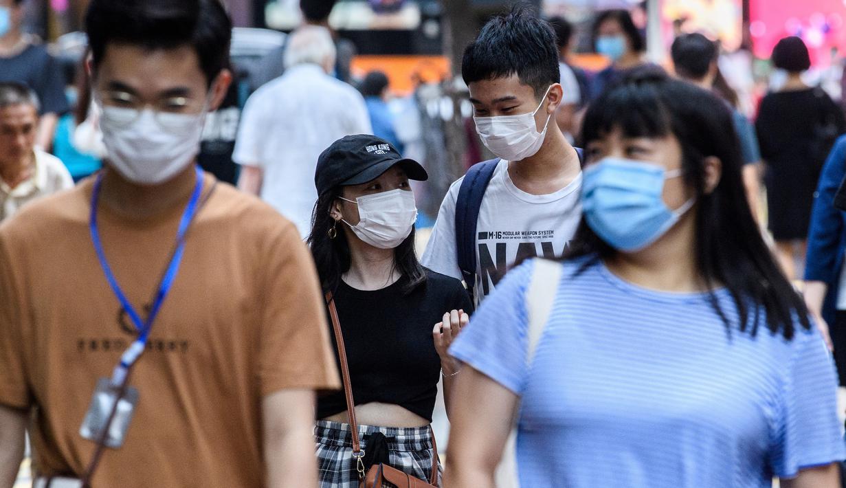Pejalan kaki mengenakan masker sebagai tindakan pencegahan Covid-19 saat berjalan di Hong Kong (13/5/2020). Dua orang di Hong Kong dinyatakan positif Covid-19, mengakhiri perjalanan 24 hari tanpa kasus baru yang mulai melonggarkan peraturan jarak sosial. (AFP/Anthony Wallace)