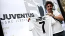 Seorang suporter, Giuseppe Strata memperlihatkan jersey Juventus atas nama Cristiano Ronaldo di depan toko resmi klub di Turin, Selasa (10/7). Berdasarkan rilis resmi dari pihak klub, Ronaldo diikat kontrak empat musim. (AFP PHOTO / Isabella Bonottovv)