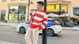 Hari Putra memang pandai memadupadankan busana, termasuk saat liburan. Dengan gaya kasual, pria kelahiran Jambi itu tampak mengenakan kaus garis-garis berwarna merah putih yang dipadukan dengan celana krem. (Liputan6.com/IG/@hariiputraa_lida2020)
