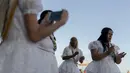 Para penganut kepercayaan Afro-Brasil bernyanyi saat memberikan persembahan untuk Yemenja sang Dewi Laut, ketika menyambut tahun baru di Pantai Copacabana di Rio de Janeiro (29/12/2019). (AFP/Mauro Pimentel)