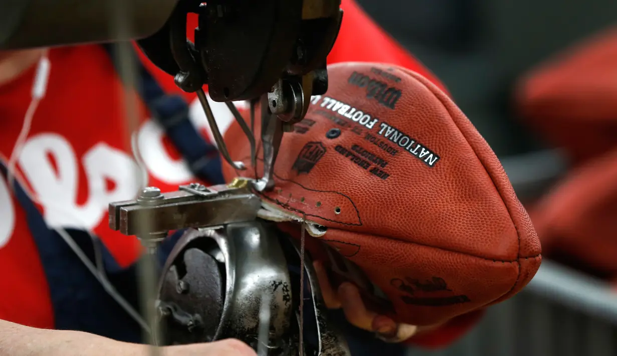 Pekerja menjahit bola american football di pabrik di Wilson Sporting Goods di  Ada, Ohio, AS (23/1). Dalam proses penjahitan, pekerja menggunakan mesin jahit lama untuk membuat sekitar 3.000 bola per hari. (AP Photo/Charles Rex Arbogast)