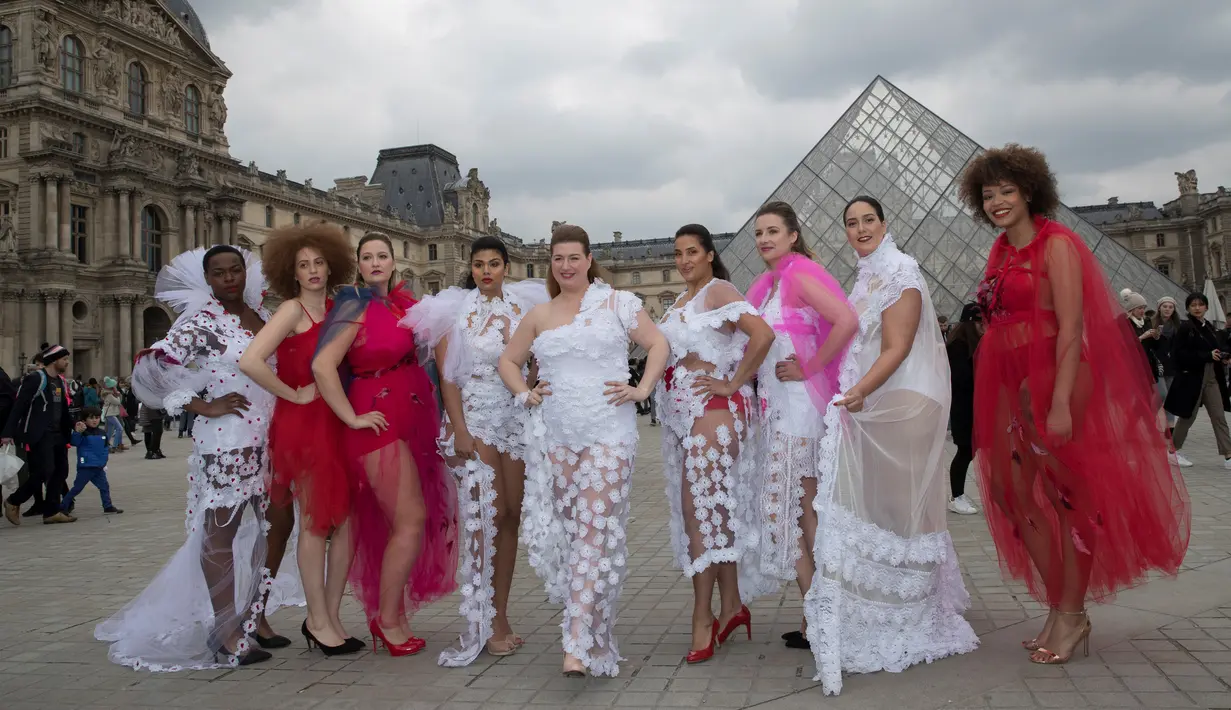 Model ukuran plus berpose di depan piramida Louvre di Paris, Prancis (4/1). Meraka melakukan catwalk di ruang publik dengan mengenakan busana layaknya di sebuah acara fashion show. (AFP/Thomas Samson)