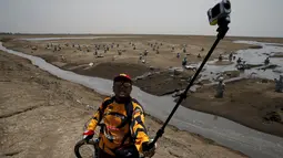 Pengendara sepeda berselfie dengan latar belakang area lumpur Lapindo di Sidoarjo, Jawa Timur, 11 Oktober 2015. Beberapa tahun silam, Porong didera bencana, namun kini kawasan tersebut malah jadi objek wisata yang tak biasa. (REUTERS/Beawiharta)