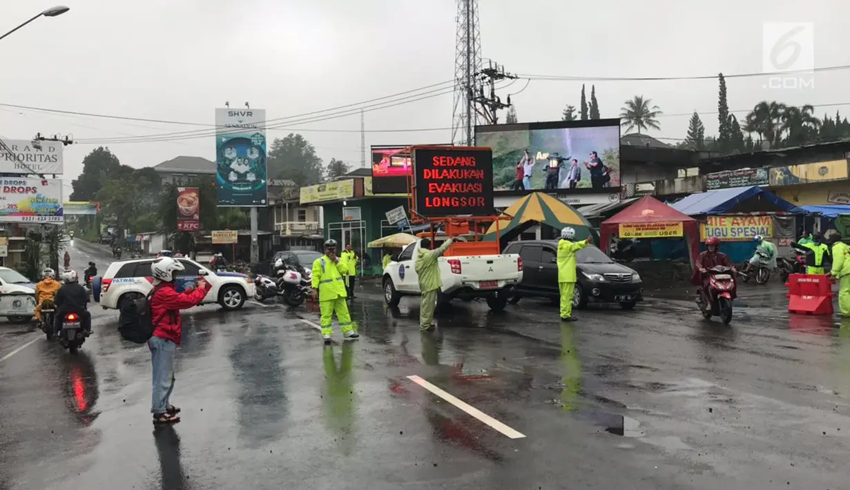 Petugas kepolisian mengalihkan arus lalu lintas saat sedang terjadi longsor di kawasan Puncak Bogor, Jawa Barat (6/2). Untuk jalur Puncak mulai dari Gunung Mas sampai Ciloto masih dilakukan penutupan. (Liputan6.com/Pool/Polres Bogor)