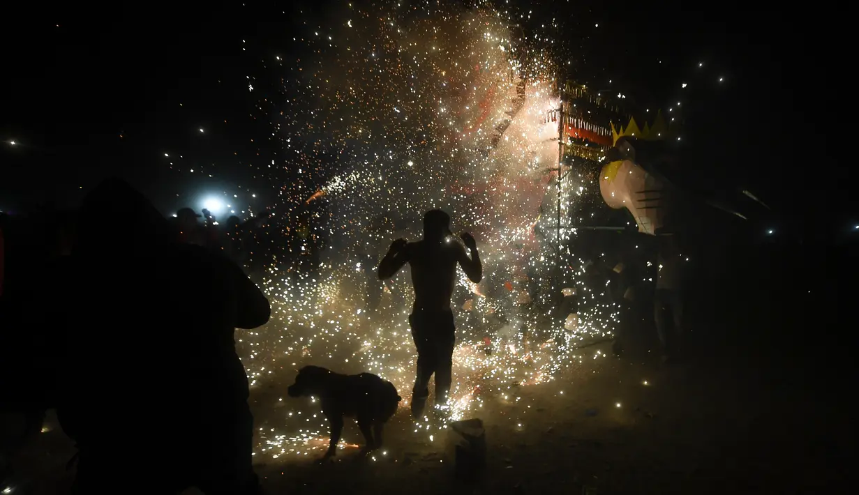 Orang-orang berlindung dari kembang api di depan "torito" (banteng kecil) tradisional yang terbuat dari kertas, kayu, dan kembang api selama perayaan San Juan de Dios di Tultepec di Mexico City (8/3/2022). (AFP/Pedro Pardo)