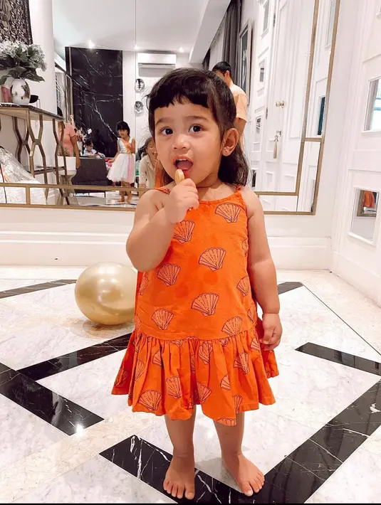<p>Dress berwarna oranye dengan motif kerang dan ruffle di bawahnya akan membuat anakmu tampil ceria dan memesona.&nbsp;(instagram/gyaps)</p>