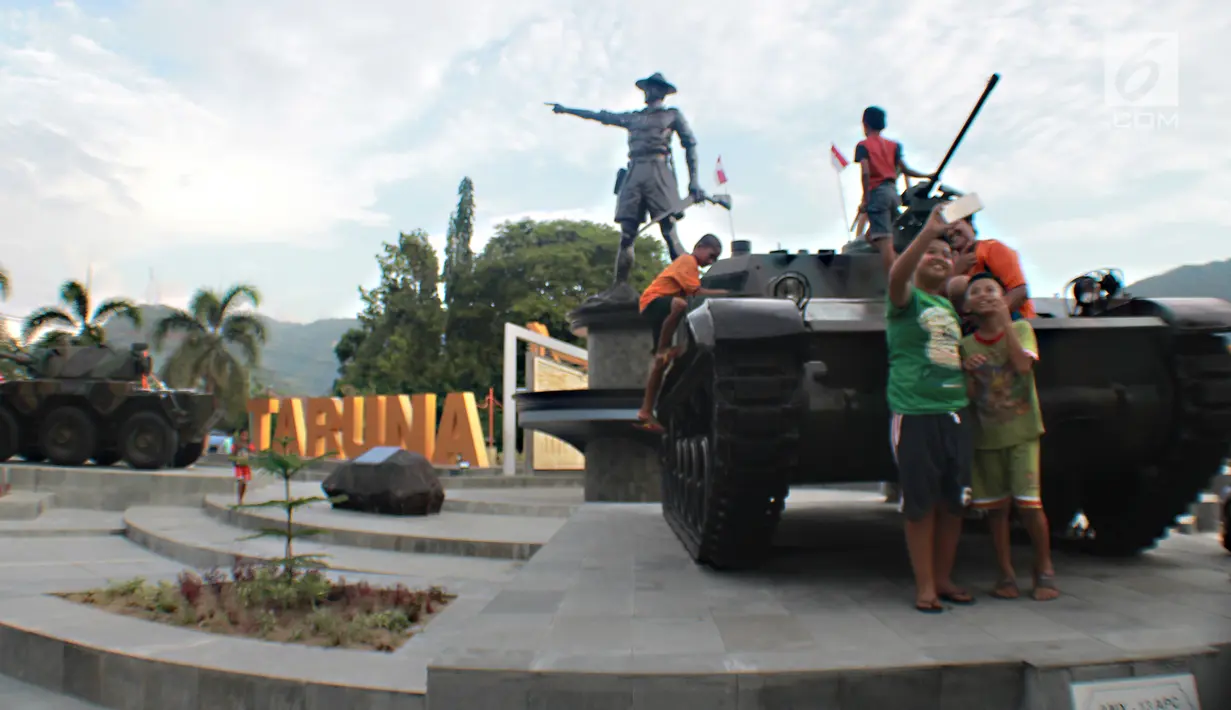 Anak-anak berswafoto dengan tank tempur bersejarah TNI yang berada di Monumen Nani Wartabone di Kilometer Nol Kota Gorontalo, Sabtu (22/9). Tank dipajang di Lapangan Taruna Remaja berdampingan dengan patung Nani Wartabone. (Liputan6.com/Arfandi Ibrahim)