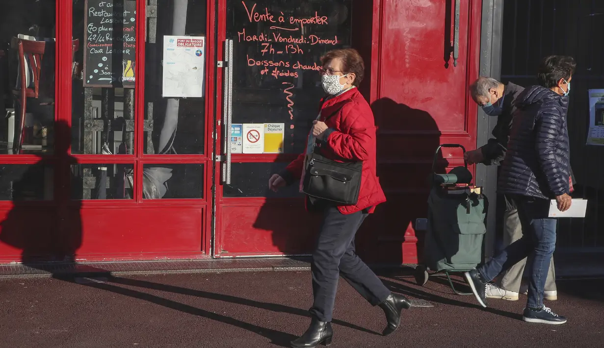 Seorang perempuan yang memakai masker berjalan melewati sebuah restoran yang tutup di Saint Germain en Laye, barat Paris, Rabu (18/11/2020). Prancis telah melampaui 2 juta kasus virus corona COVID-19 yang dikonfirmasi, total tertinggi keempat di dunia. (AP Photo/Michel Euler)