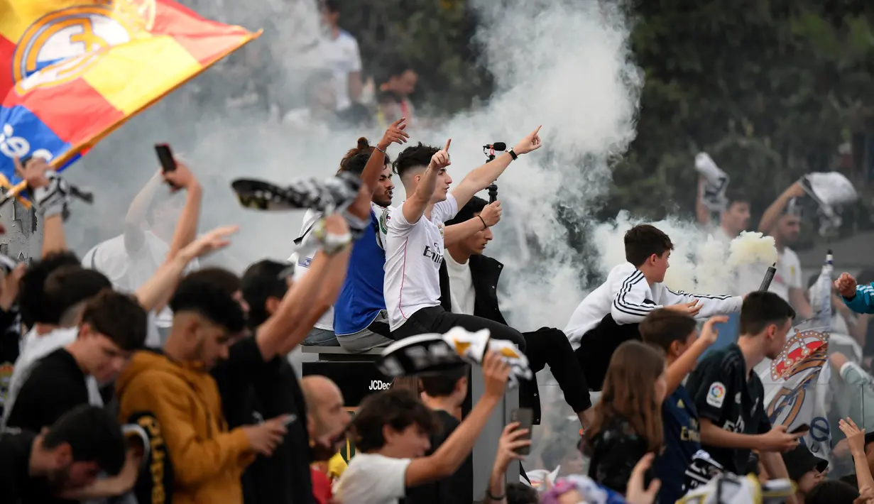 <p>Suporter Real Madrid berkumpul merayakan trofi La Liga Spanyol di alun-alun Plaza Cibeles di Madrid pada 30 April 2022. Real Madrid mengamankan gelar La Liga ke-35  setelah kemenangan kandang 4-0 atas Espanyol. (AFP/Oscar Del Pozo)</p>