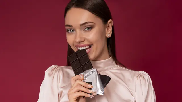 Seorang perempuan sedang menggigit sebuah cokelat (Foto Dok: Freepik/freepik)
