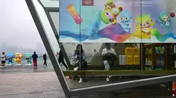 Sejumlah orang duduk di dalam stan yang dihiasi poster Asian Games 2022 di sepanjang kawasan pedestrian Sungai Qiantang di Hangzhou, Zhejiang,China pada 22 September 2023 waktu setempat. (AFP/Manan Vatsyayana)