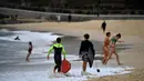 Orang-orang berjalan-jalan di Pantai Maroubra yang dibuka kembali untuk aktivitas warga di tengah pembatasan sosial yang diberlakukan di kala wabah corona (Covid-19) di Sydney, Australia (20/4/2020). (AFP/Saeed Khan)