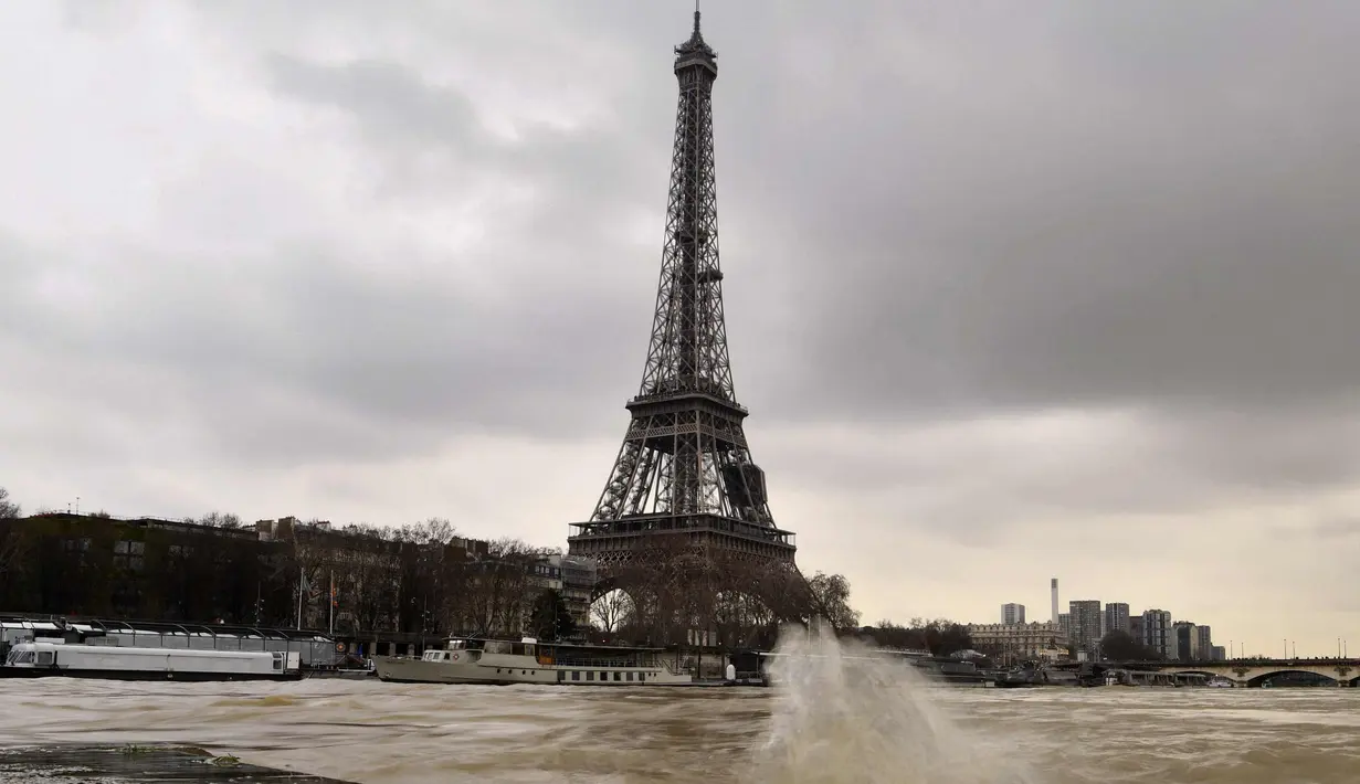 Menara Eiffel terlihat saat sungai Seine di Paris meluap, Prancis (6/1). Sungai Seine tidak mampu menampung debit air setelah hujan terjadi terus-menerus. (AFP Photo/Christophe Simon)