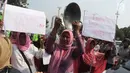 Seorang ibu dari Barisan Emak-Emak Militan Indonesia membawa wajan saat menggelar aksi di seberang Istana Merdeka, Jakarta, Rabu (18/7). Massa juga membawa berbagai tulisan berisi tuntutan untuk menurunkan harga bahan pokok. (Liputan6.com/Arya Manggala)