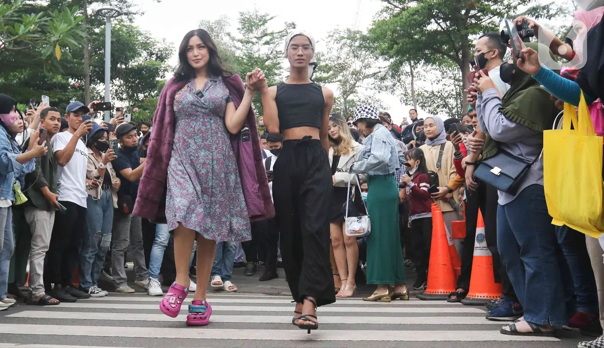 Artis Jessica Iskandar berlenggak-lenggok di zebra cross Dukuh Atas saat meramaikan Citayam Fashion Week di kawasan SCBD (Sudirman Citayam Bojong Gede Dukuh Atas), Dukuh Atas, Jakarta Pusat, Senin (25/7/2022). Jessica Iskandar tampak anggun mengenakan gaun bunga-bunga dengan luaran blazer bewarna ungu. (Liputan6.com/Herman Zakharia)