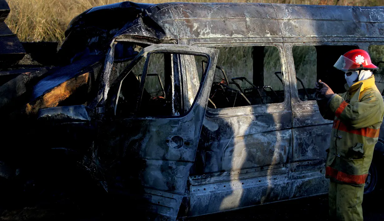 Petugas pemadam kebakaran berada di lokasi kecelakaan antara sebuah van dan truk kargo  di jalan raya Negara Bagian Jalisco, Meksiko, Rabu (18/12/2019). Sedikitnya 14 orang tewas,termasuk lima anak-anak dan 12 lainnya mengalami luka dalam kecelakaan tersebut . (Ulises Ruiz / AFP)