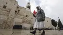 Seorang biarawati Kristen berjalan menjelang Natal di luar Gereja Kelahiran Yesus di kota Bethlehem, Tepi Barat pada 22 Desember 2022. Beberapa tempat indah yang diincar pengunjung menyambut Natal di Kota Bethlehem adalah Gereja Kelahiran yang sudah berusia ratusan tahun. (AFP/Hazem Bader)