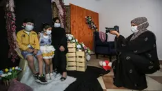 Seorang wanita dan anak-anak mengenakan masker berpose saat difoto  pada liburan Idul Fitri Muslim selama pandemi virus coronavirus COVID-19 di studio foto Palestina Faten Issa's studio di Rafah di Jalur Gaza selatan (27/5/2020). (AFP/Said Khatib)