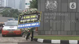 Petugas berjalan membawa karangan bunga duka cita atas meninggalnya Ratu Elizabeth II untuk diletakkan di depan Kedutaan Besar (Kedubes) Inggris, kawasan Kuningan, Jakarta, Jumat (9/9/2022).  Ratu Elizabeth II menghembuskan napas terakhir di rumah liburannya yakni Kastil Balmoral, Skotlandia. (Liputan6.com/Herman Zakharia)