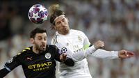 Gelandang Manchester City, Bernardo Silva, duel udara dengan bek Real Madrid, Sergio Ramos, pada laga liga Champions di Stadion Santiago Bernabeu, Rabu(26/2/2020). Manchester City menang dengan skor 2-1. (AP/Bernat Armangue)