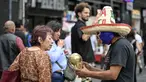 Seorang pedagang kaki lima yang mengenakan topeng gulat tradisional Meksiko menunjukkan suvenir berbentuk piala Piala Dunia kepada pejalan kaki di Mexico City, Senin 8 Juni 2026. (Yuri CORTEZ/AFP)