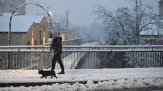 Seorang wanita berjalan-jalan dengan seekor anjing di tengah salju di Milan, Italia (28/12/2020). Hujan salju mengguyur Milan pada Senin (28/12). (Xinhua/Daniele Mascolo)