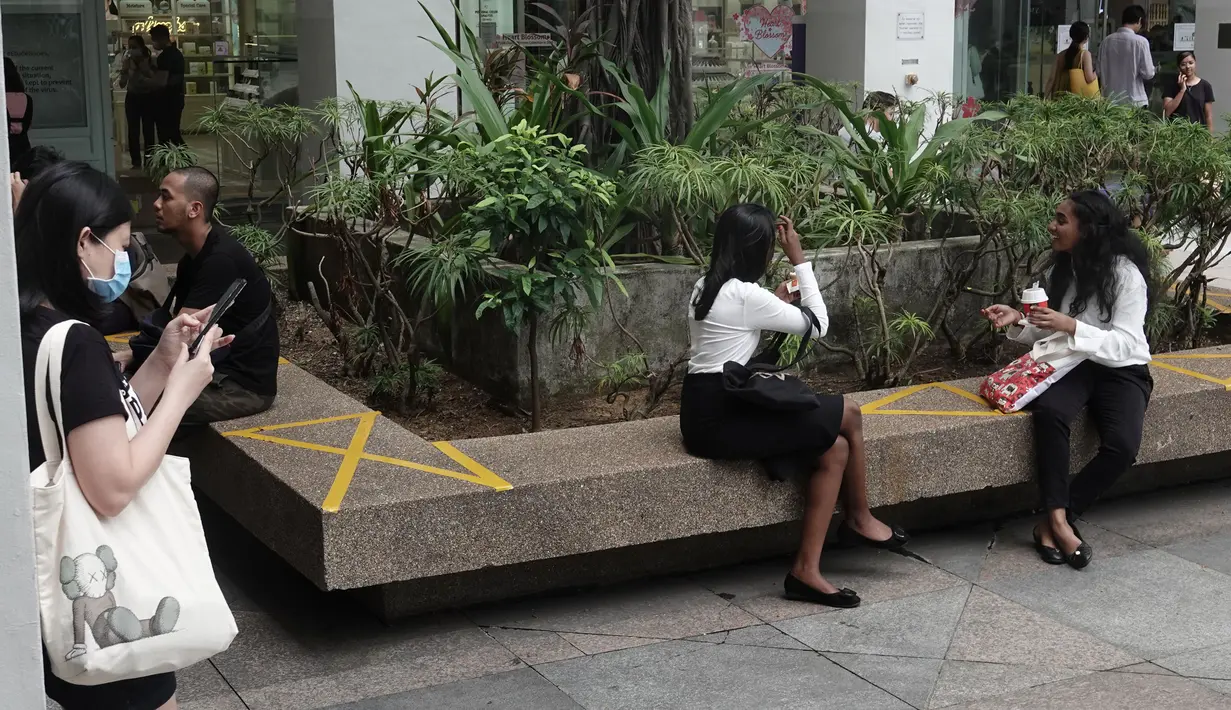 Pusat perbelanjaan menerapkan langkah social distancing atau jaga jarak sosial dengan memberikan tanda silang di area tempat duduk publik di wilayah Bugis Singapura, 28 Maret 2020. Warga di Singapura yang melanggar perintah jaga jarak akan dikenakan denda sekitar Rp 1112 juta. (Xinhua/Then Chih Wey)