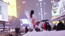 Seorang wanita berfoto di tengah salju di Times Square, New York, Amerika Serika (16/12/2020). Badai salju besar pertama di musim ini menyebabkan badai salju besar di tiga negara bagian, menumpahkan lebih dari satu kaki salju di beberapa bagian. (Xinhua/Wang Ying)