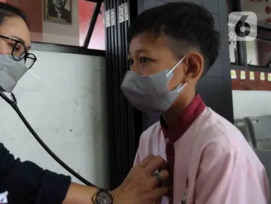 Dokter memeriksa kesehatan anak Sekolah Dasar Negeri 06 Lubang Buaya, Jakarta, Jumat (25/8/2023). Pemeriksaan dilakukan untuk menskrining kemungkinan anak-anak terjangkit Infeksi Saluran Pernapasan Akut (ISPA). (merdeka.com/Imam Buhori)