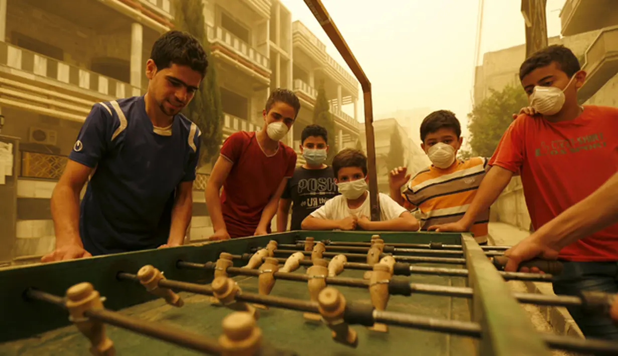 Sejumlah anak mengenakan masker sambil bermain bola meja di Provinsi Homs, Suriah, Senin  (7/8/2015).  Badai ini membuat sebagian rumah sakit menghentikan kegiatannya.  (REUTERS/Omar Sanadiki)