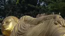 Burung merpati berdiri di atas patung Buddha raksasa di Vihara Maha Vihara Mojopahit di Mojokerto pada 4 Juni 2023. Proses pembersihan dan pemeliharaan patung Buddha Tidur di Vihara ini juga sudah dilakukan jelang Hari Raya Waisak. (AFP/Juni Kriswanto