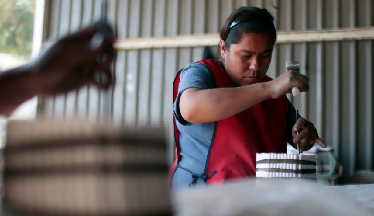 Seorang wanita mengisi bubuk mesiu untuk membuat petasan di Tultepec, Meskiko (22/12). Kota Tultepec ini memang dikenal sebagai lokasi utama pabrik pembuat petasan di Meksiko. (AFP/Pedro Pardo)
