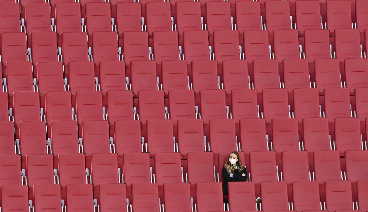 Seorang wanita duduk di tribun penonton yang kosong dalam pertandingan Liga Jerman antara Augsburg melawan Bayer Leverkusen, Minggu (21/2/2021). (Foto: AFP/Berbagai Sumber/Christof Stache)