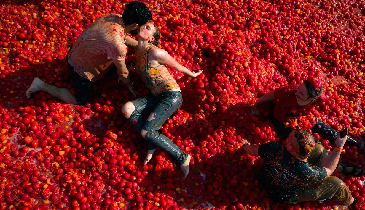 Seorang peserta berbaring di atas tomat yang hancur ketika berpartisipasi dalam festival 'Tomatina' di St.Petersburg, Rusia, Minggu (18/8/2019). Tomatina atau perang tomat adalah festival Spanyol, dan tahun ini merupakan pertama kalinya dirayakan di Rusia. (AP Photo/Dmitri Lovetsky)