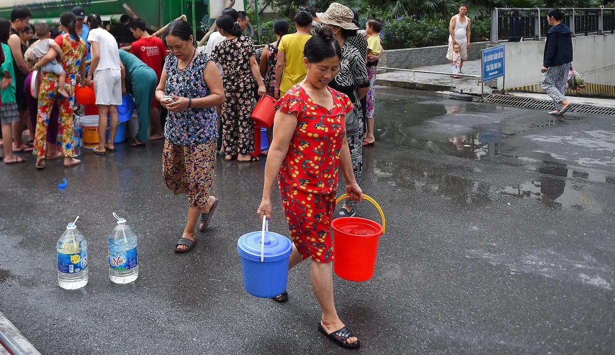 Warga membawa wadah berisi air usai mengisinya dari truk tangki pasokan pemerintah di Hanoi, Vietnam, Kamis (17/10/2019). Pemerintah memberi bantuan air bersih setelah zat penyebab kanker karsinogen mencemari air ledeng beberapa daerah di Hanoi. (Nhac NGUYEN/AFP)