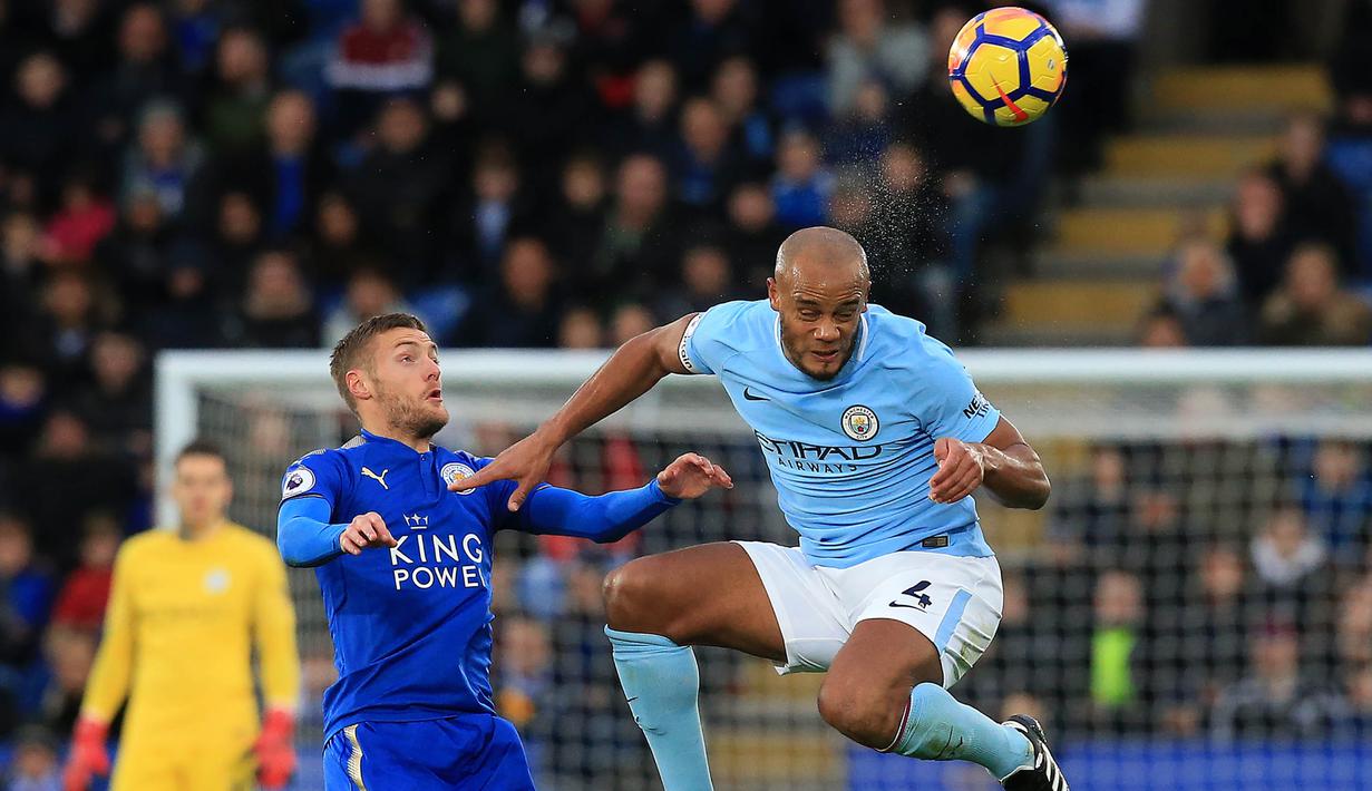 Bek Manchester City, Vincent Kompany, berebut bola dengan striker Leicester City, Jamie Vardy, pada laga Premier League di Stadion King Power, Sabtu (18/11/2017). Manchester City menang 2-0 atas Leicester City. (AFP/Lindsey Parnaby)