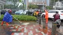 Petugas Penanganan Prasarana dan Sarana Umum (PPSU) membersihkan saluran air di kawasan Gelora Bung Karno, Jakarta, Selasa (17/12/2019). Petugas PPSU membersikan saluran air saat terjadi genangan usai hujan deras mengguyur Jakarta. (Liputan6.com/Herman Zakharia)
