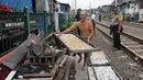 Seorang warga sekitar menyikirkan barang miliknya saat dilakukan penertiban lapak dan bangunan liar di sepanjang jalur kereta di kawasan Grogol, Jakarta Barat, Kamis (22/2). (Liputan6.com/Arya Manggala)