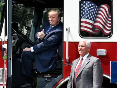 Presiden AS, Donald Trump mengacungkan jempol sambil duduk di sebuah truk pemadam kebakaran saat bersama Wapres Mike Pence menghadiri acara pameran produk bertajuk "Made in America" di Gedung Putih, Washington, Senin (17/7). (Olivier Douliery/AFP)