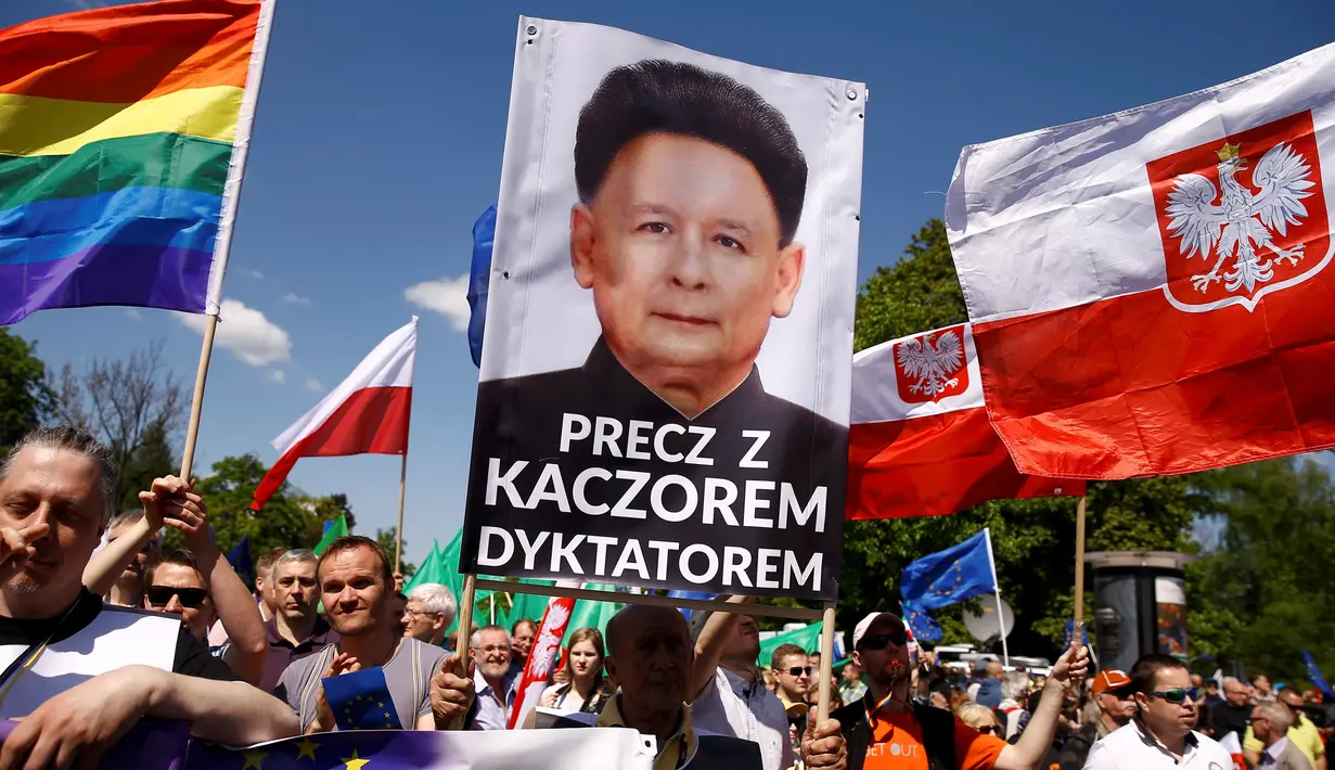 Pengunjuk rasa membawa berbagai atribut saat memprotes pemerintahan baru Polandia yang dipegang oleh partai konservatif di Warsaw, Sabtu (7/5). Massa mengepung Ibu Kota guna menuntut perubahan hukum dan peradilan yang baru dibuat. (REUTERS/Kacper Pempel)