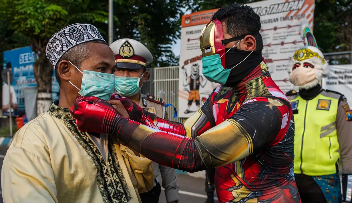 Petugas kepolisian berpakaian superhero memakaikan masker kepada warga di jalan kawasan Pasuruan, Jawa Timur, Kamis (9/4/2020). Hal tersebut bertujuan untuk mengantisipasi penyebaran Virus Corona (COVID-19). (JUNI KRISWANTO / AFP)