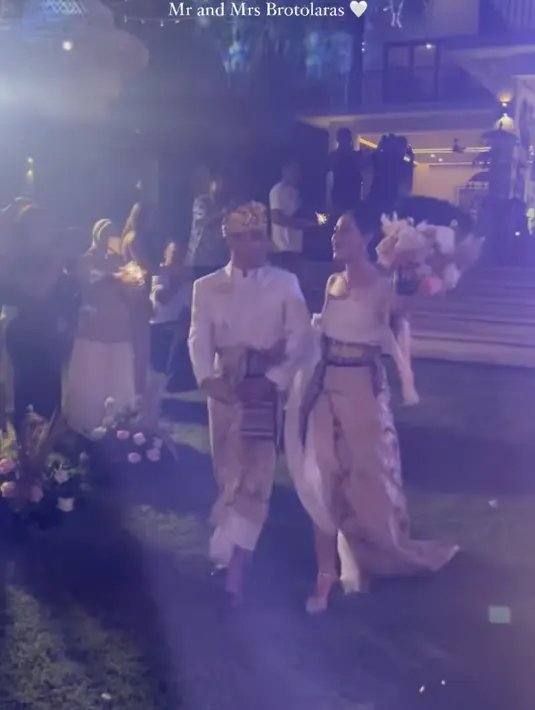 Untuk busana pengantin resepsi, Laura Theux memakai atasan warna putih dan kain Bali. Begitu juga Indra yang memakai kemeja kerah tinggi dan udeng emas. [Foto: @rantymaria]