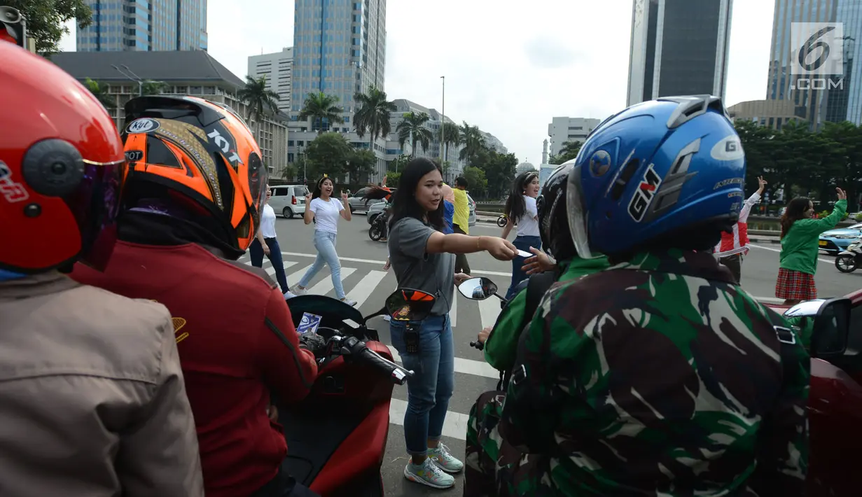 Sejumlah mahasiswi membagikan stiker kepada pengendara saat mengampanyekan keselamatan berlalu lintas di Jakarta, Rabu (20/3). Aksi ini mengajak pengendara untuk tertib berlalu lintas dengan #SelamatDijalan. (merdeka.com/Imam Buhori)